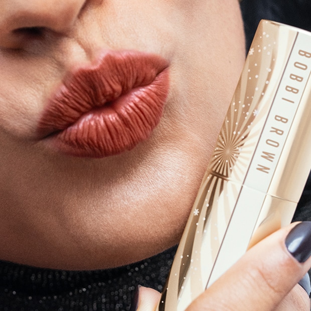 Close up of model applying Crushed-Oil Infused Gloss to lips